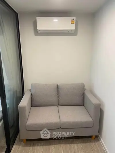 Cozy living room with modern gray sofa and air conditioning unit, perfect for relaxation.