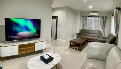 Spacious modern living room with elegant furniture and large TV, perfect for relaxation and entertainment.