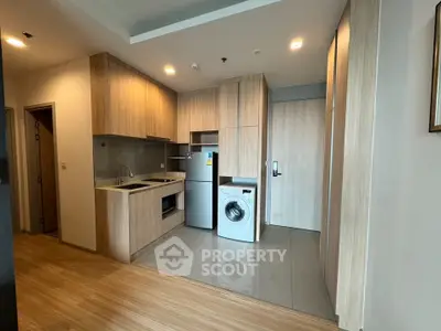 Modern kitchen with wooden cabinets, fridge, and washing machine in a stylish apartment.