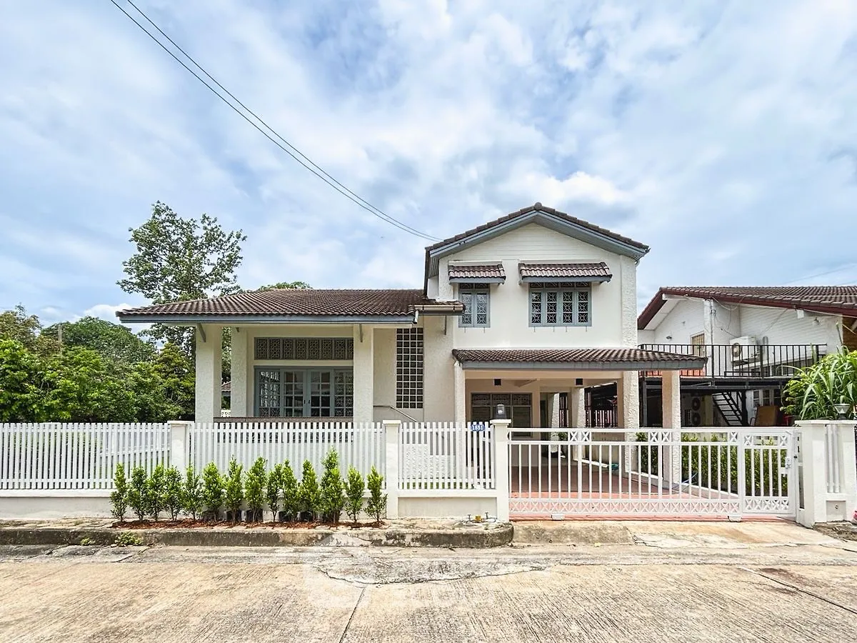 Charming two-story house with white picket fence and lush greenery, perfect family home in a serene neighborhood.