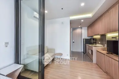 Modern open-layout living room with sleek kitchen and cozy seating area in a stylish apartment.