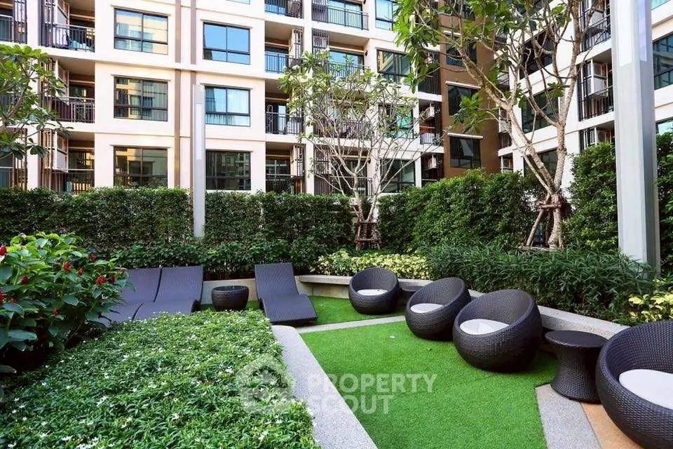 Modern apartment building with lush garden and stylish outdoor seating area.