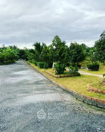Scenic view of a lush garden pathway with tropical plants and trees, perfect for serene living.