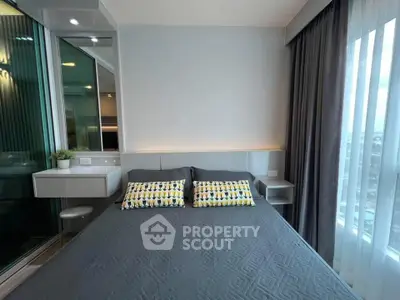 Modern bedroom with stylish decor and large window offering natural light.