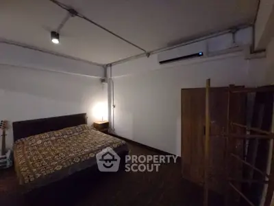 Spacious bedroom with modern lighting and air conditioning, featuring a cozy bed and wooden wardrobe.