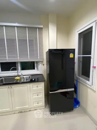 Modern kitchen with sleek black fridge and white cabinetry