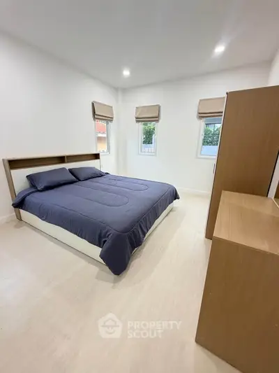 Spacious bedroom with modern decor and natural light, perfect for relaxation and comfort.