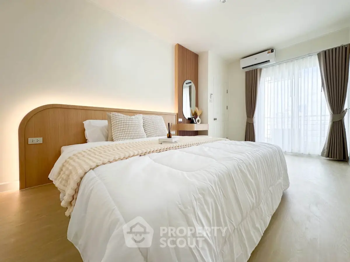 Spacious and bright bedroom with modern decor and large window for natural light.