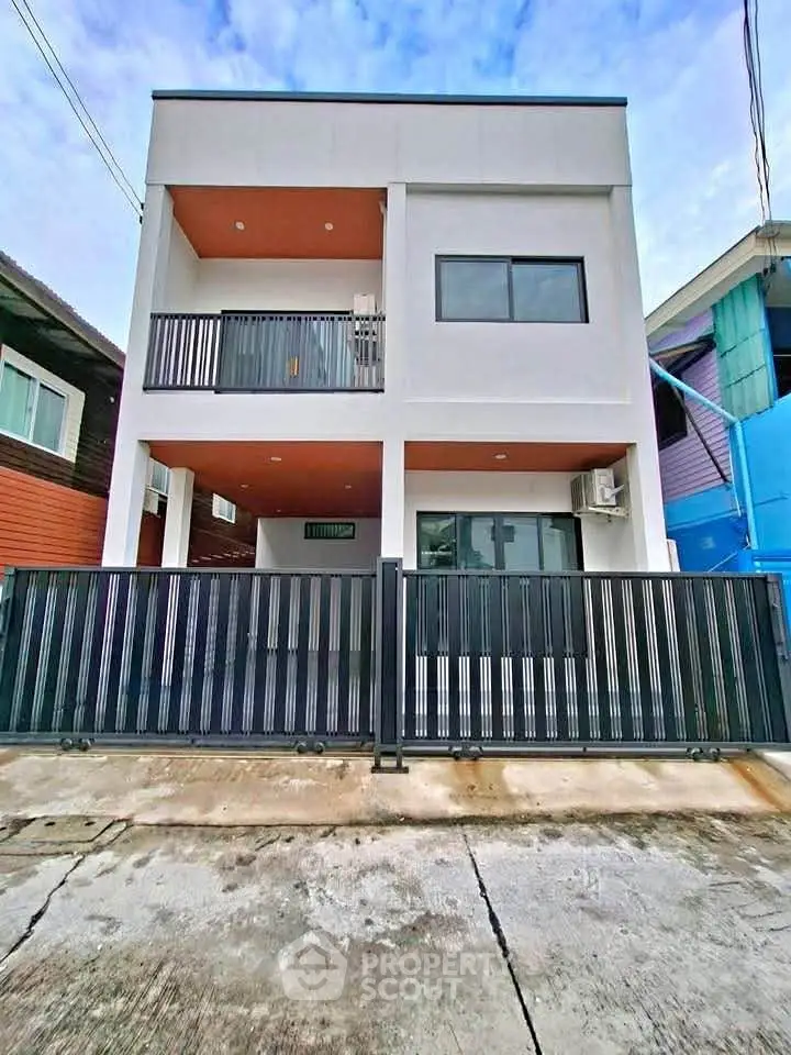 Modern two-story house with sleek design and gated entrance in a suburban neighborhood.