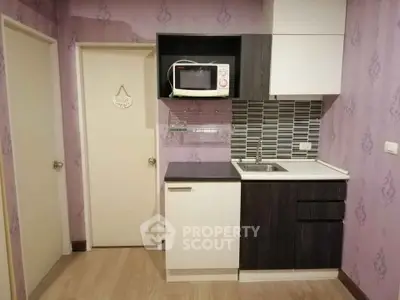 Compact kitchen with modern cabinetry and microwave in cozy apartment