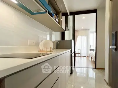 Modern kitchen with sleek cabinetry and open layout leading to a bright bedroom.