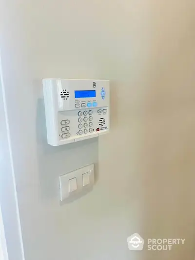 Modern home security system keypad on wall in a contemporary interior setting.