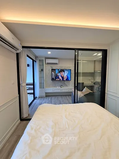 Modern bedroom with sliding glass doors and view into stylish living area