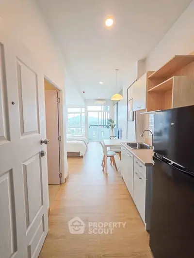 Modern apartment interior with open kitchen and cozy bedroom view.