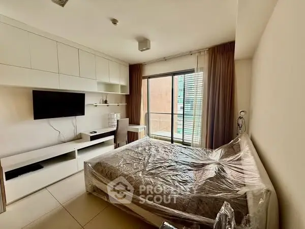 Modern bedroom with balcony access, featuring sleek built-in storage and natural light.