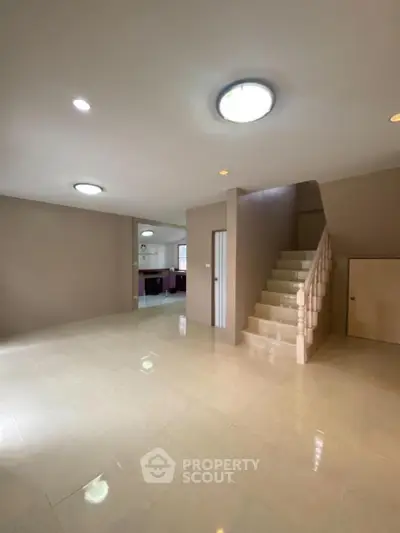 Spacious open-plan living area with modern staircase and tiled flooring