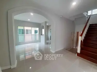 Spacious modern living room with glossy tile flooring and wooden staircase.
