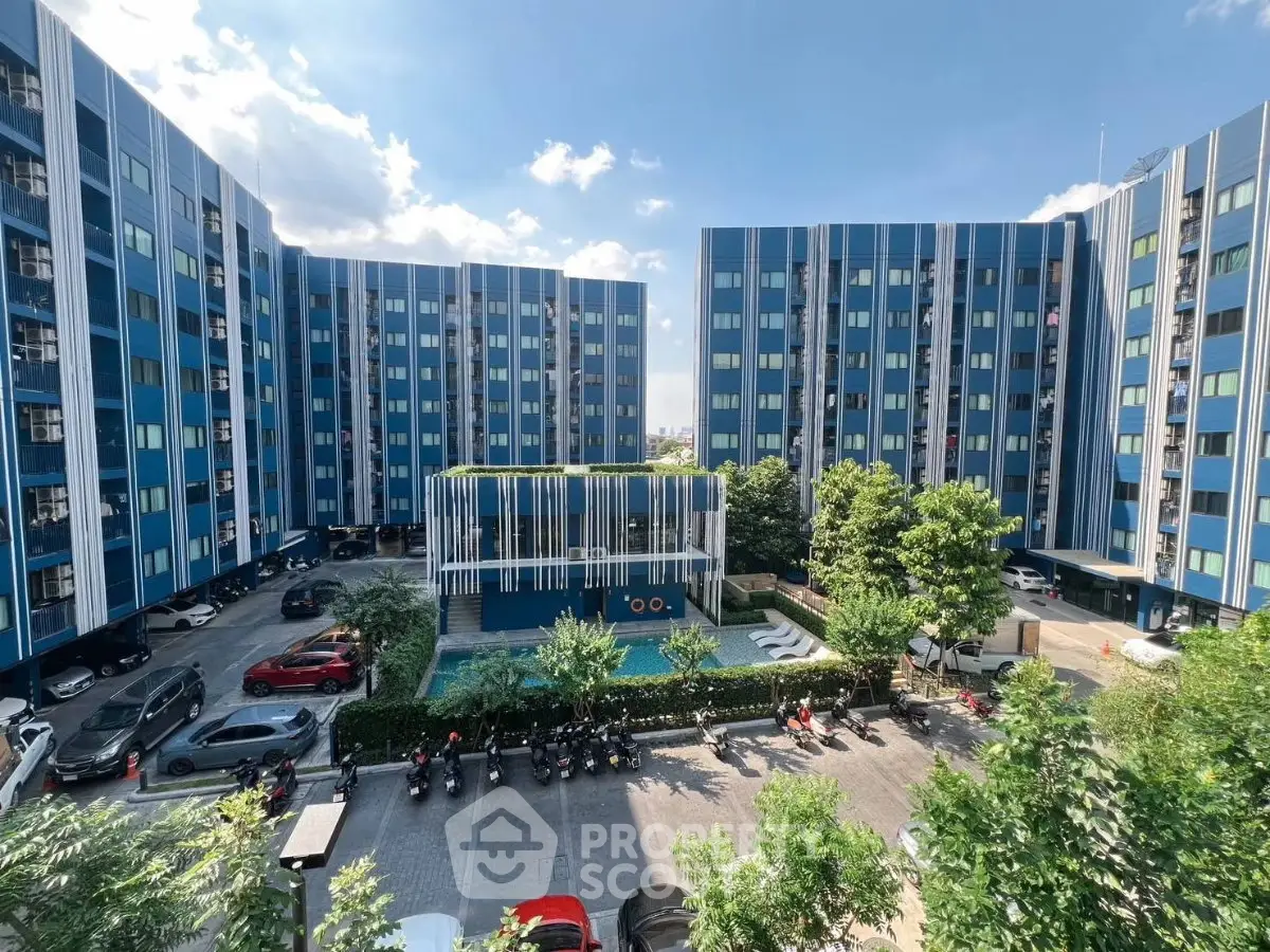 Modern blue apartment complex with central courtyard and parking area