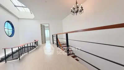 Elegant hallway with modern railing and chandelier in a bright, airy home.