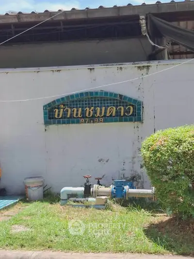 Exterior view of a building with a tiled sign and garden area.