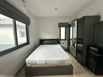 Modern bedroom with sleek black furniture and large window offering natural light.