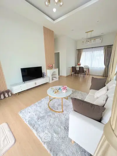 Elegant living room with modern decor and natural light, featuring a cozy seating area and stylish dining space.