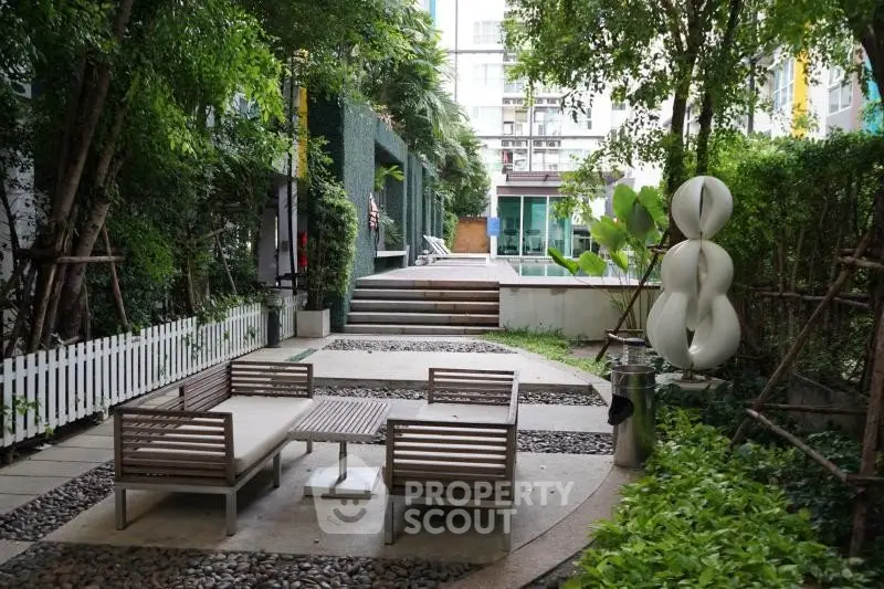 Charming garden area with modern seating and lush greenery in a residential complex.