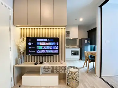 Modern living room with sleek TV setup and open kitchen layout in stylish apartment.