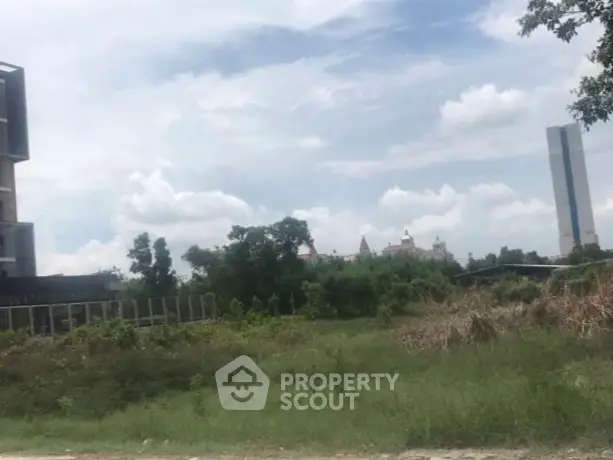 Expansive plot with lush greenery and distant skyline view, perfect for development.