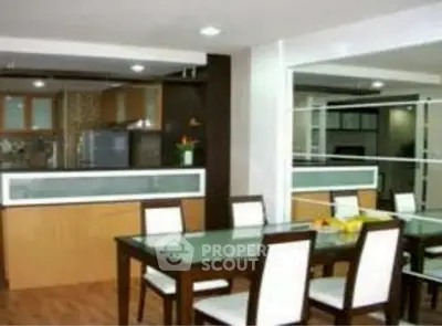 Modern dining area with glass table and open kitchen layout in stylish apartment.