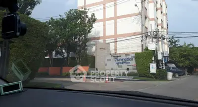 Modern urban condominium entrance with lush greenery and clear signage