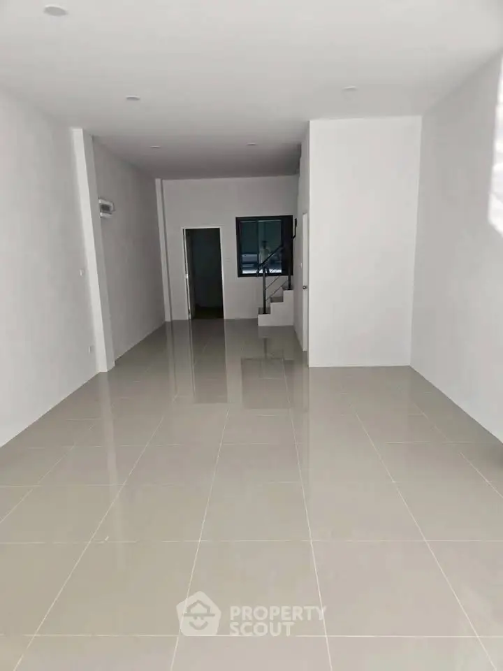 Spacious open-plan living area with sleek tiled flooring and modern design.