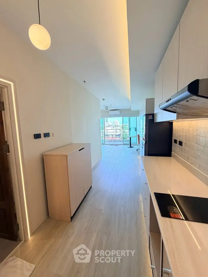Modern kitchen with sleek cabinetry and open layout leading to a bright living area with balcony view.