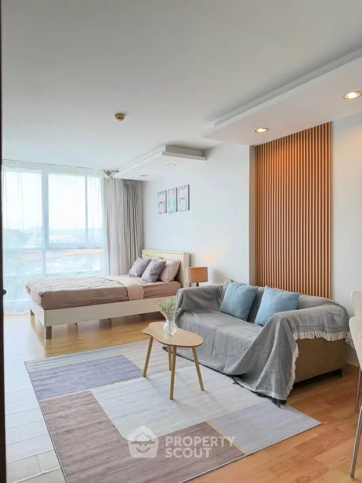 Modern open-plan living room and bedroom with stylish decor and natural light.