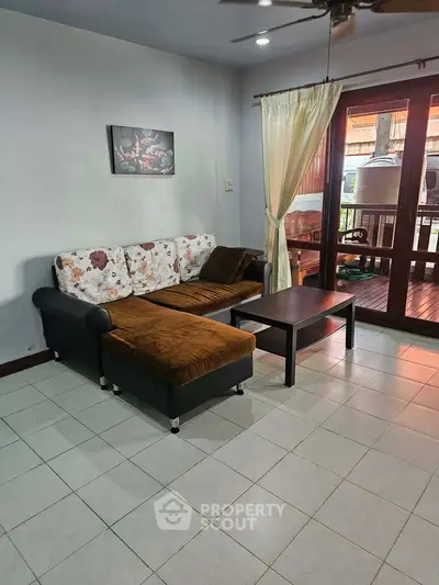 Cozy living room with floral sofa and wooden coffee table, opening to a charming balcony view.