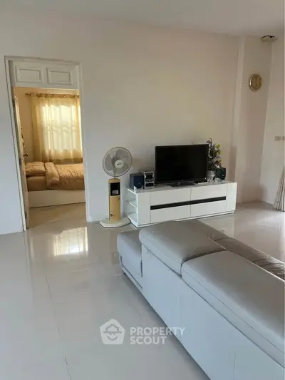 Spacious living room with modern decor and view into cozy bedroom