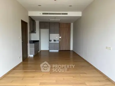 Spacious modern apartment with open layout and wooden flooring, featuring a compact kitchen area.