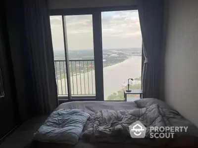 Stunning bedroom with panoramic river view from high-rise apartment window.