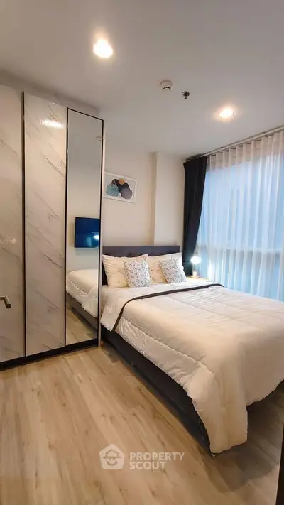 Modern bedroom with stylish decor and large window in a cozy apartment.