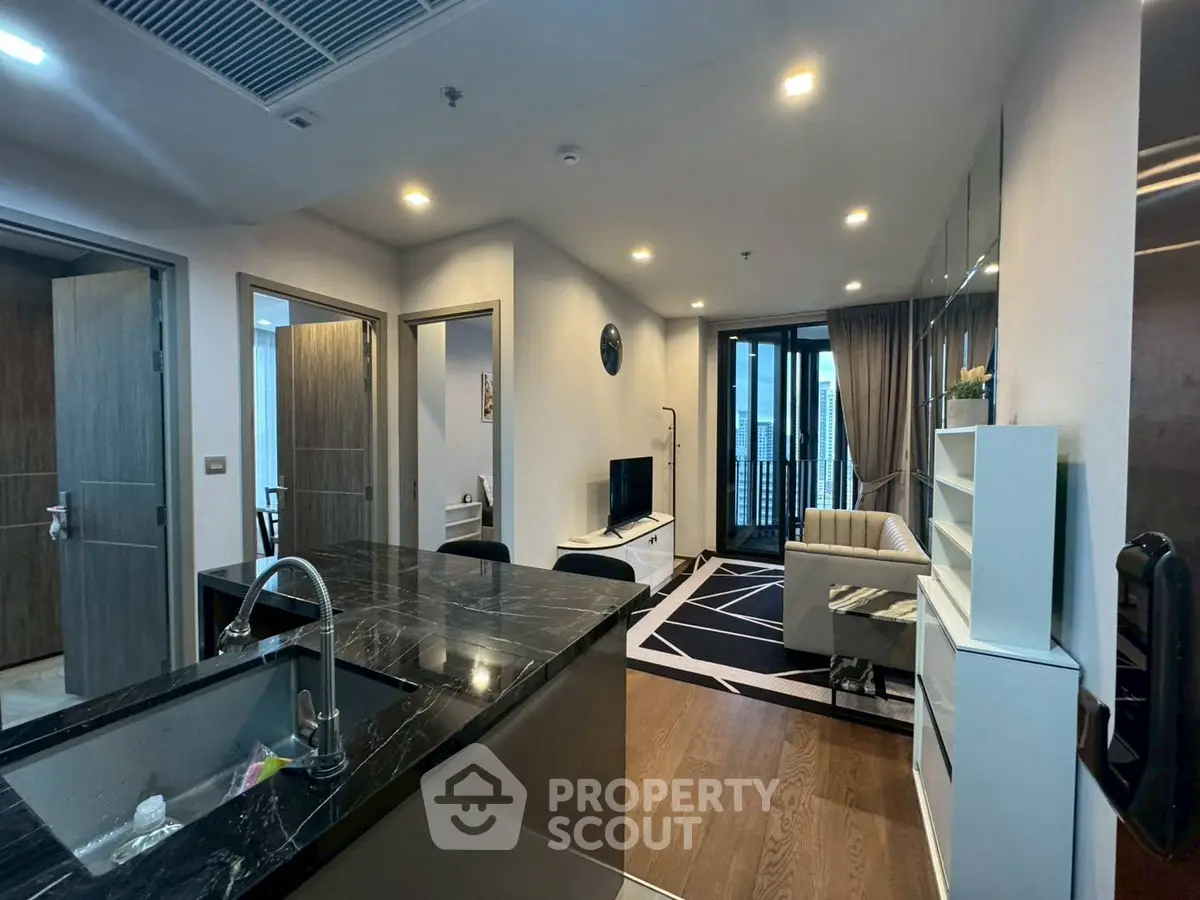 Modern open-plan living room with sleek kitchen and balcony access