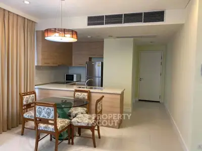 Modern kitchen with dining area, featuring wooden cabinets and stainless steel appliances.