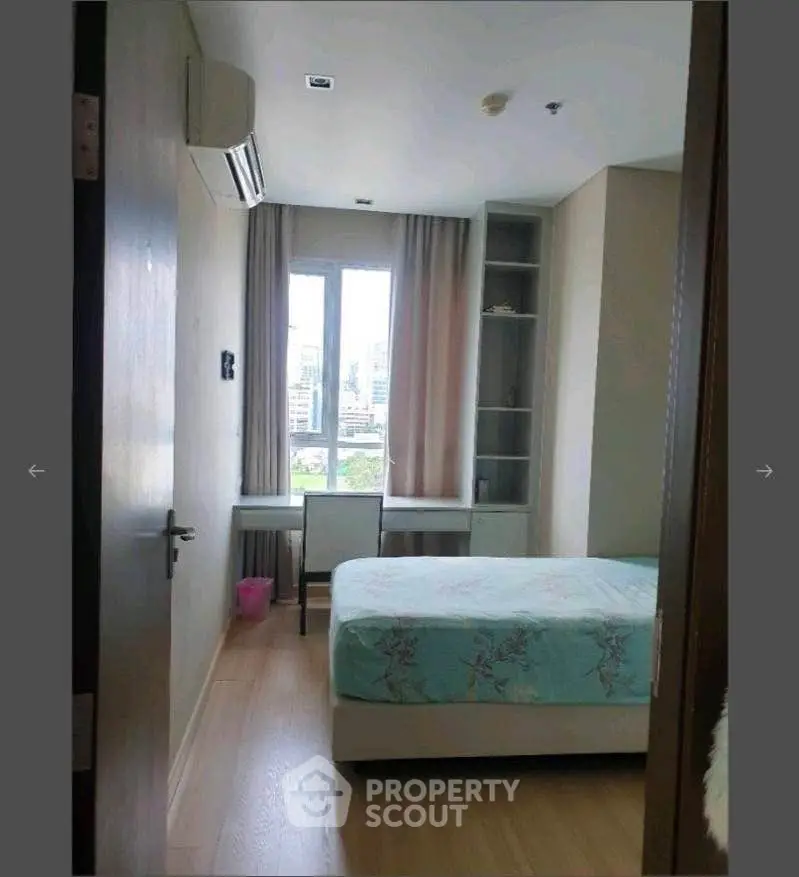 Cozy bedroom with city view, featuring a comfortable bed and study desk, perfect for urban living.