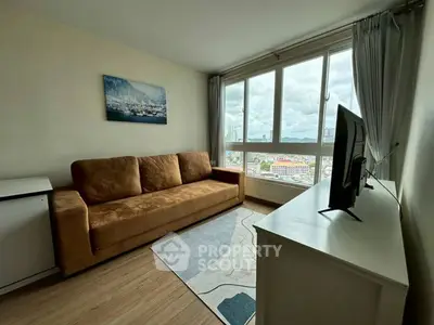 Cozy living room with large windows offering stunning city views, featuring a comfortable sofa and modern TV setup.