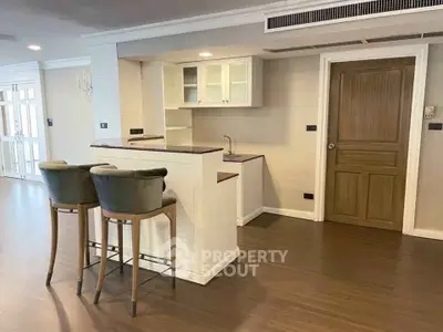 Spacious open-layout kitchen with modern bar stools and elegant wooden flooring.