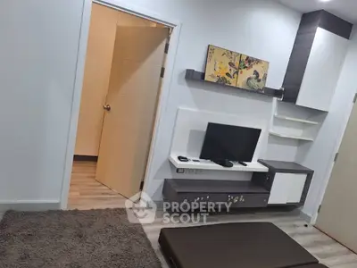 Modern living room with sleek TV unit and open door to adjacent room.
