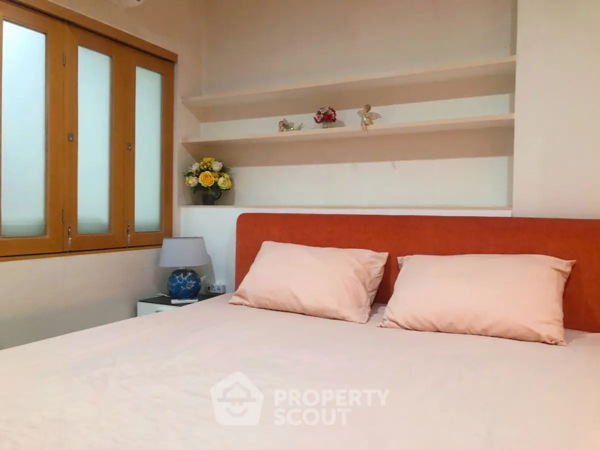 Cozy bedroom with orange headboard and built-in shelves, perfect for relaxation.