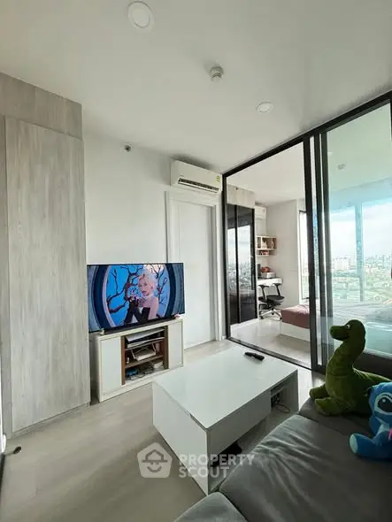 Modern living room with sliding glass doors and city view, featuring stylish decor and natural light.