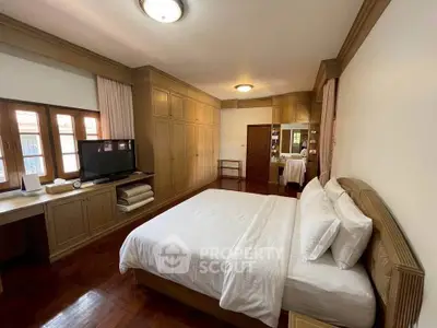 Spacious bedroom with elegant wooden furnishings and ample natural light.