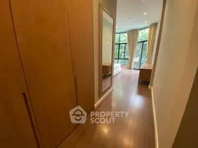 Spacious bedroom with large windows and wooden flooring, offering a serene view.