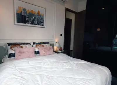 Cozy bedroom with modern decor and cityscape artwork, featuring plush pillows and sleek furnishings.
